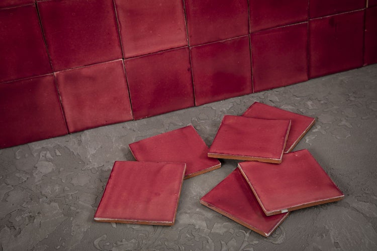 Rote quadratische Fliesen auf grauem Untergrund