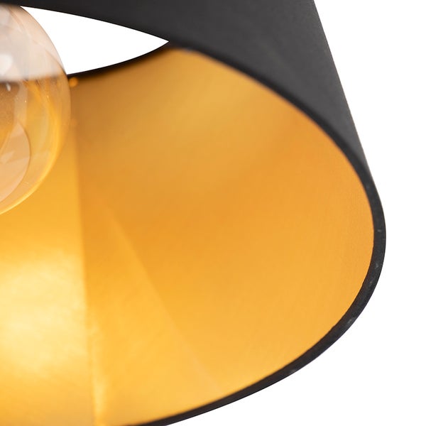 Nahaufnahme eines Lampenschirms mit schwarzer Stoffaußenseite und goldfarbener Innenseite.