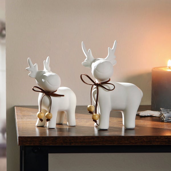 Zwei weiße Elchfiguren mit Schleife auf einem Tisch