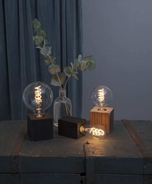 Dekorative Lampen mit Holzsockel und Glühbirne auf einem Tisch