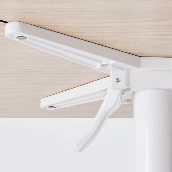 Weißer Klappmechanismus für ein Tischbein unter einer hellen Tischplatte in Holzoptik.