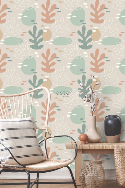 Szene mit einer Esta Home Tapete mit Pflanzenmuster, einem Stuhl und dekorativen Gegenständen.