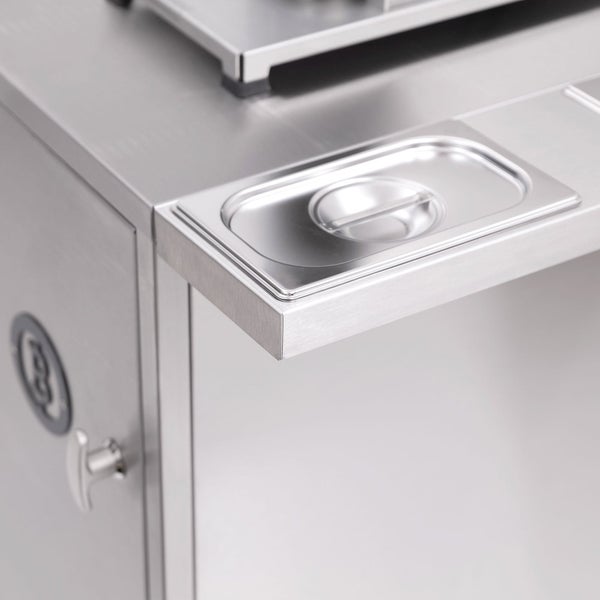 Detailansicht eines Küchenmoduls aus gebürstetem Edelstahl mit integriertem Behälter mit Deckel auf der Seitenablage.