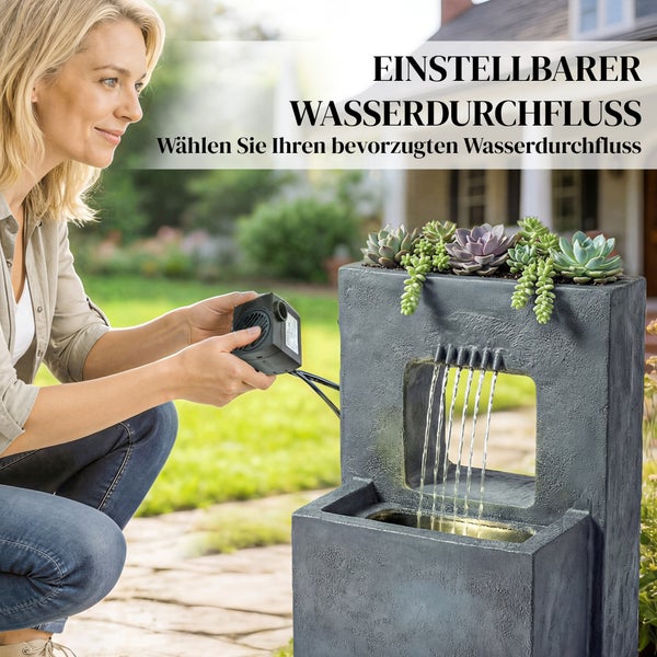 Frau stellt den Wasserdurchfluss einer kleinen schwarzen Pumpe für einen grauen Gartenbrunnen mit Sukkulenten ein.