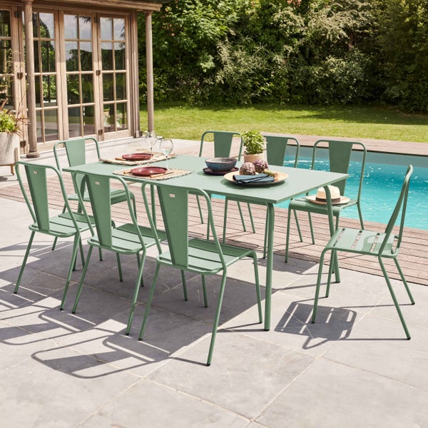 Grünes Garten-Set aus Metall mit rechteckigem Tisch und acht Stühlen auf einer Steinterrasse neben einem Pool und einem Gartenhaus.