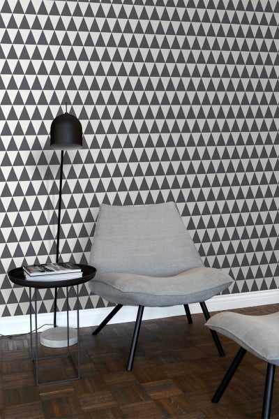 Wohnzimmer mit grafischer Tapete, Sessel, Beistelltisch und Stehlampe