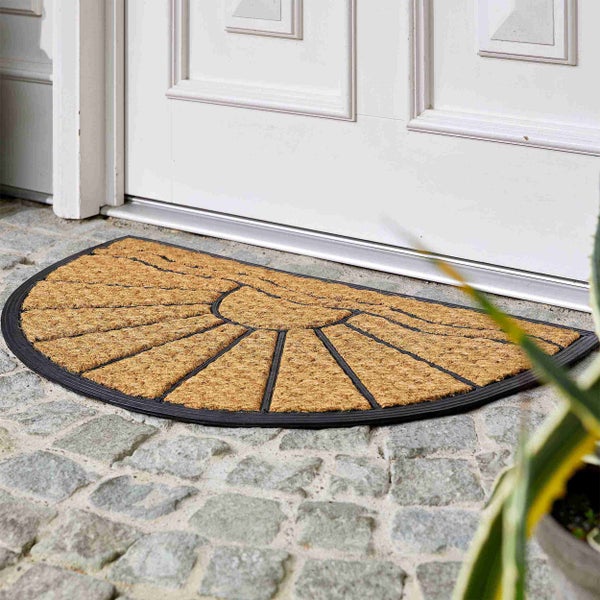 Halbrunde Fußmatte aus Kokos vor einer Haustür.