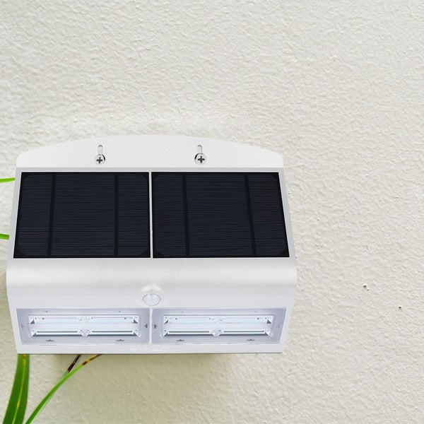 Weiße LED-Solarleuchte für den Außenbereich mit Bewegungsmelder an einer Wand montiert