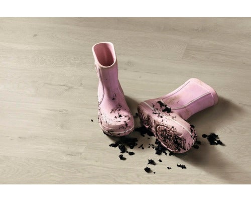 Schmutzige Kindergummistiefel auf hellem Boden