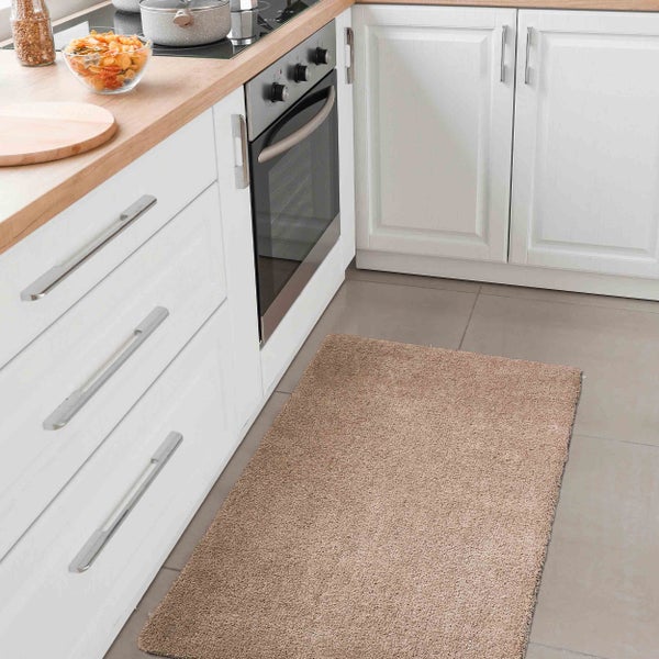 Küchenszene mit hellem Teppich, weißen Schränken und hölzerner Arbeitsplatte