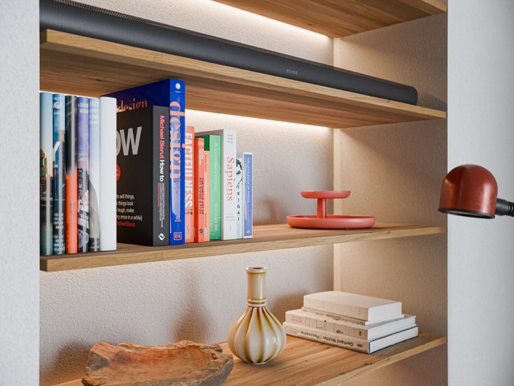 Modernes beleuchtetes Nischenregal aus Holz mit Büchern, Dekorationsgegenständen und einer Soundbar mit Sonos Logo.