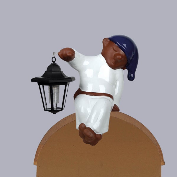 Gartenfigur schlafendes Männchen in weißem Schlafanzug und blauer Schlafmütze mit schwarzer Solar-Laterne.