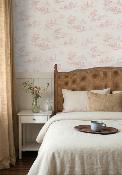 Hell eingerichtetes Schlafzimmer mit klassischer Toile de Jouy Tapete, einem Holzbett mit Rattankopfteil und einem weißen Nachtschrank.