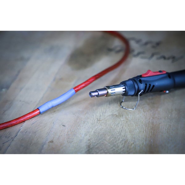 Verschiedene tropische Obstpflanzen wie Mango und Avocado in Töpfen mit Holzstäben in einem Gewächshaus auf gepflastertem Boden.