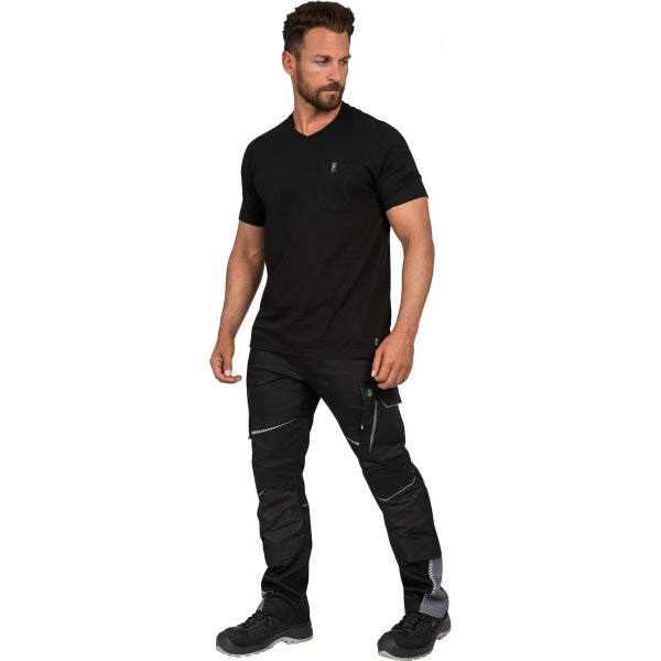 Ein Mann trägt ein schwarzes V-Ausschnitt T-Shirt, eine schwarze Arbeitshose mit praktischen Taschen und schwarze Sicherheitsschuhe.