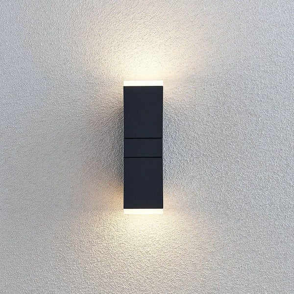 Rechteckige Wandleuchte in Schwarz mit Up-and-Down-Lichteffekt an einer strukturierten Wand.