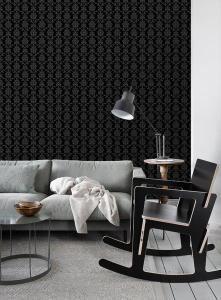 Wohnzimmer mit Couch, Lampe und schwarzer Tapete mit Ornamenten