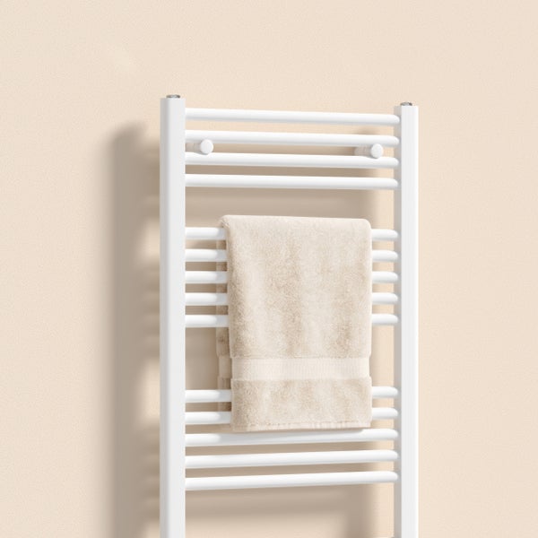Weißer Badheizkörper als Handtuchwärmer mit waagerechten Sprossen und einem beige Handtuch.