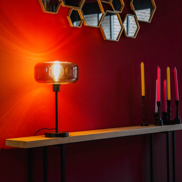 Dekorative Tischleuchte auf einem Holztisch mit Spiegeln und Kerzen im Hintergrund.