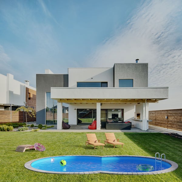 Garten mit modernem Haus, Pool, Liegestühlen und Rasenfläche