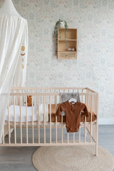Kinderzimmer mit Babybett, Mobile, Wandregal und Teppich