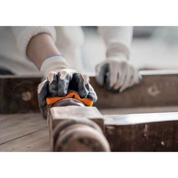 Person schleift Holz mit einem Schleifschwamm und Handschuhen