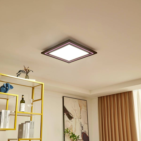 Quadratische LED-Deckenleuchte mit schwarzem Rahmen, weißem Licht und pinkem Lichtrand in einem modern eingerichteten Wohnraum.