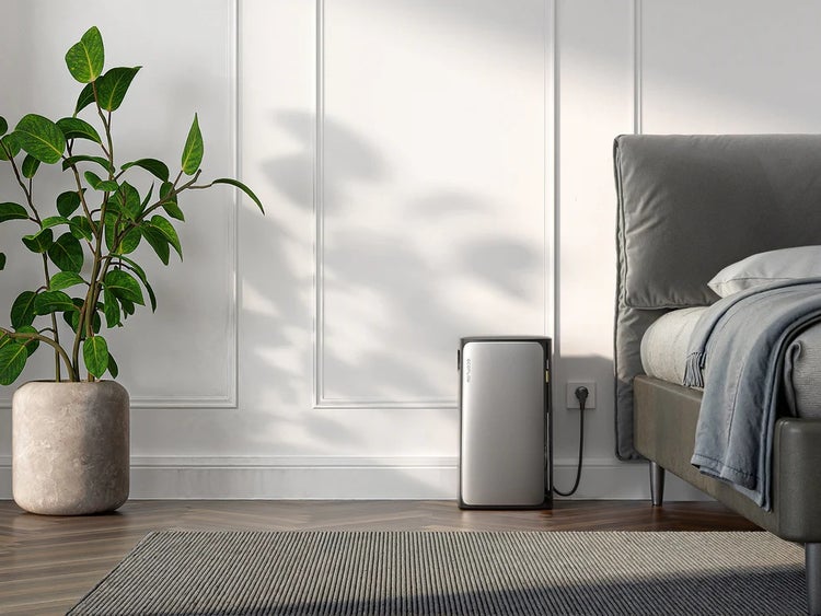 EcoFlow PowerStream Mikrowechselrichter in einem hellen, modern eingerichteten Schlafzimmer an eine Steckdose angeschlossen, neben Bett und Pflanze.