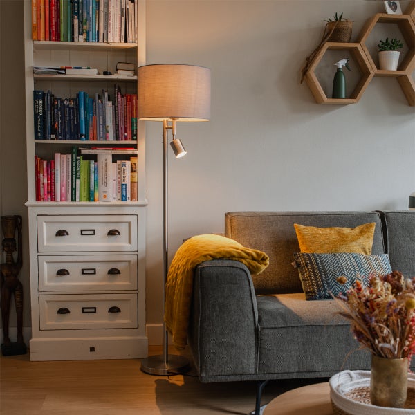 Wohnzimmer mit Stehlampe, Sofa, Bücherregal und Dekorationsartikeln