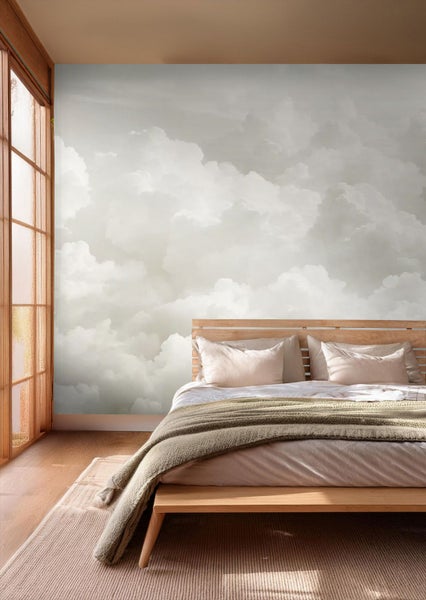 Fototapete mit Wolkenmotiv in einem hellen Schlafzimmer mit Holzbett und strukturiertem Teppich.