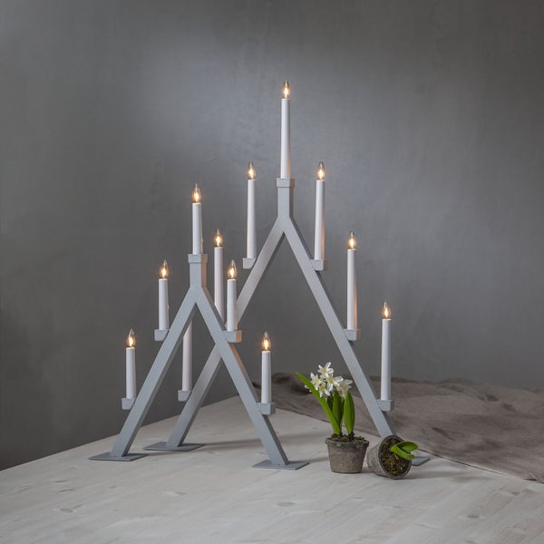 Zwei graue, dreieckige elektrische Adventsleuchter mit Kerzen auf einem Holztisch