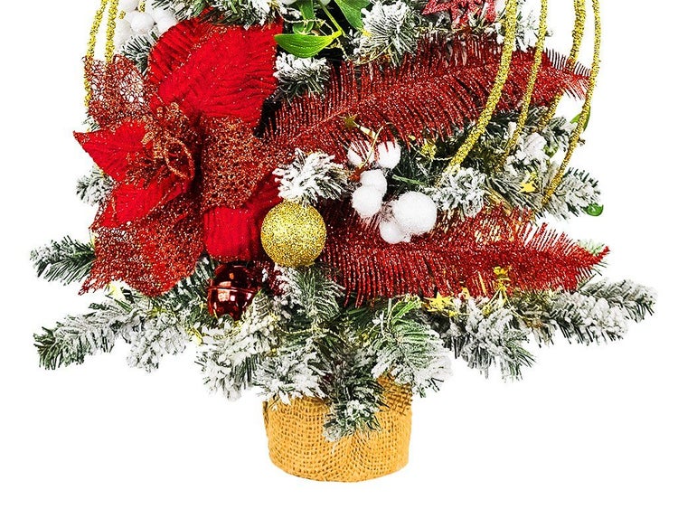 Künstlicher Weihnachtsbaum in Jutesack, dekoriert mit Weihnachtssternen, Kugeln und Beeren mit Kunstschnee.