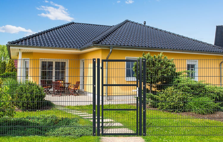 Drahtzaun mit Gartentür vor einem Wohnhaus