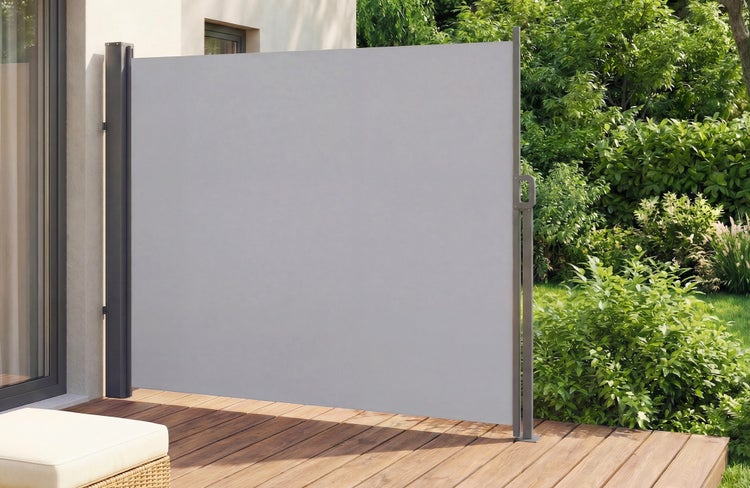Ausziehbare Seitenmarkise aus Stoff mit Metallpfosten auf einer Holzterrasse als Sichtschutz vor einem Garten.