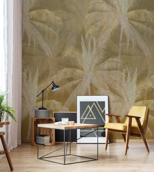 Wohnraum mit Vliestapete mit Palmenmuster in einem warmen Design, kombiniert mit einem Sessel und einem modernen Couchtisch aus Holz und Metall.