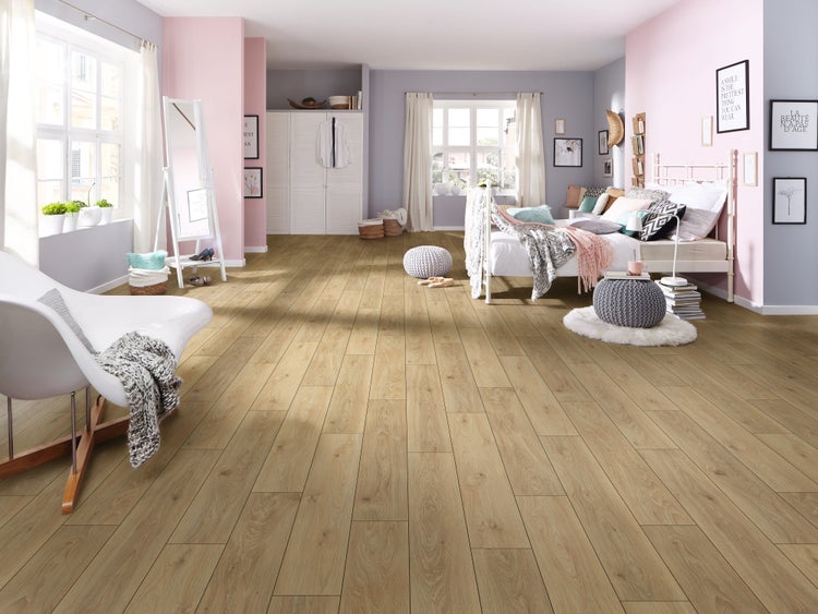 Helles Laminat in Eichenoptik verlegt in einem geräumigen, modern eingerichteten Schlafzimmer mit pastellfarbenen Wänden und weißem Bett.