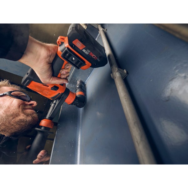 Handwerker mit Schutzbrille bohrt mit einem Akku Winkelschleifer oder Bohrschrauber ein Loch in eine Metallwand