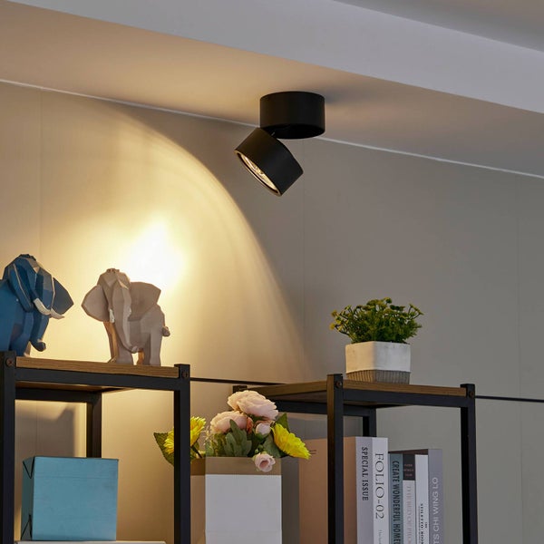 Deckenleuchte aus Metall über einem Regal mit Dekoration und Büchern