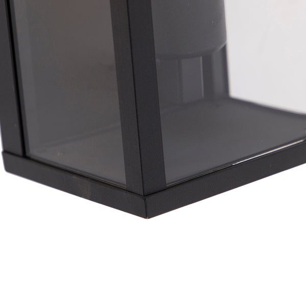 Nahaufnahme der unteren Ecke einer modernen rechteckigen Außenwandleuchte mit Metallrahmen und getöntem Glas.