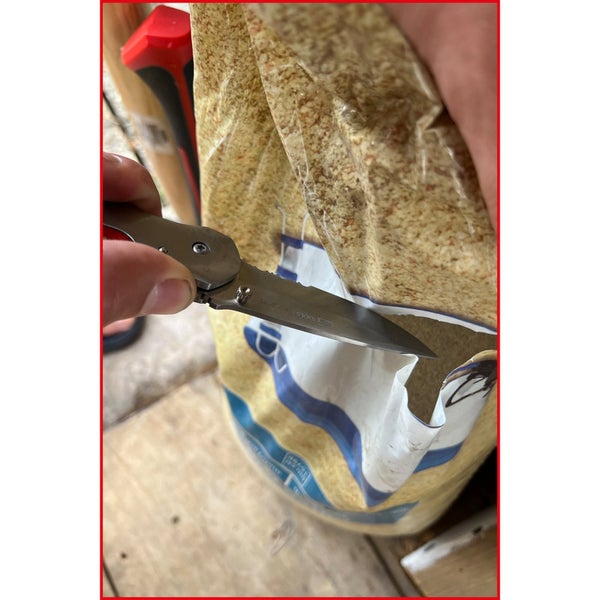 Ein Messer öffnet eine Packung Vogelfutter.