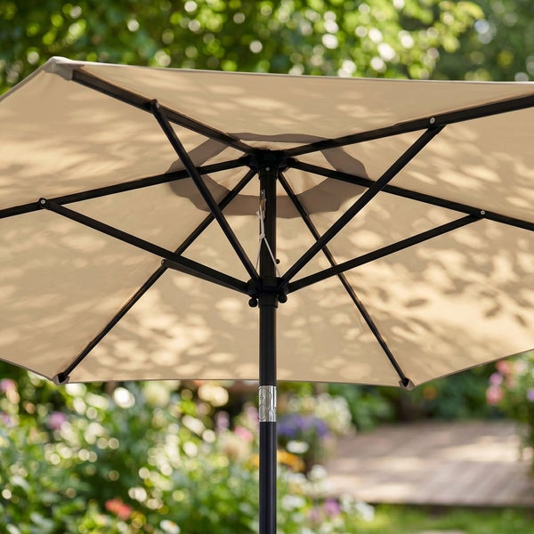 Unteransicht eines geöffneten Sonnenschirms mit schwarzem Metallgestell und beiger Bespannung im Garten.