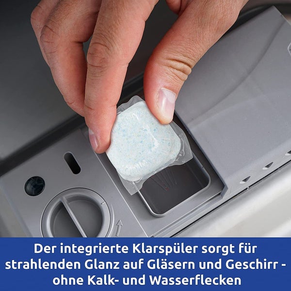 Eine Hand legt einen Geschirrspülertab in die Spülmaschine