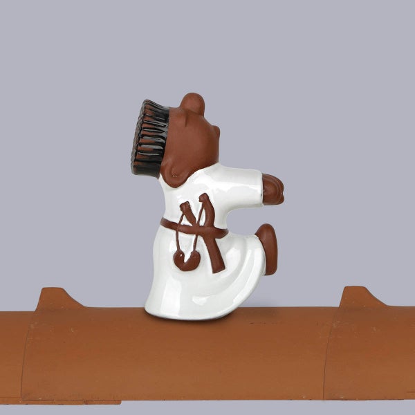 Firstfigur Schornsteinfeger aus Keramik in sitzender Position auf einem Firstziegel.