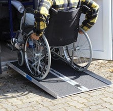 Person im Rollstuhl fährt eine Rampe hinauf.