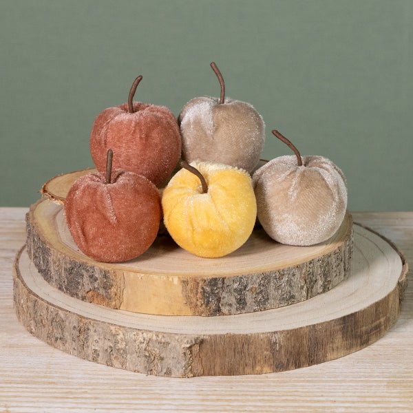 Dekorative Äpfel aus Samt auf Holzscheiben gestapelt
