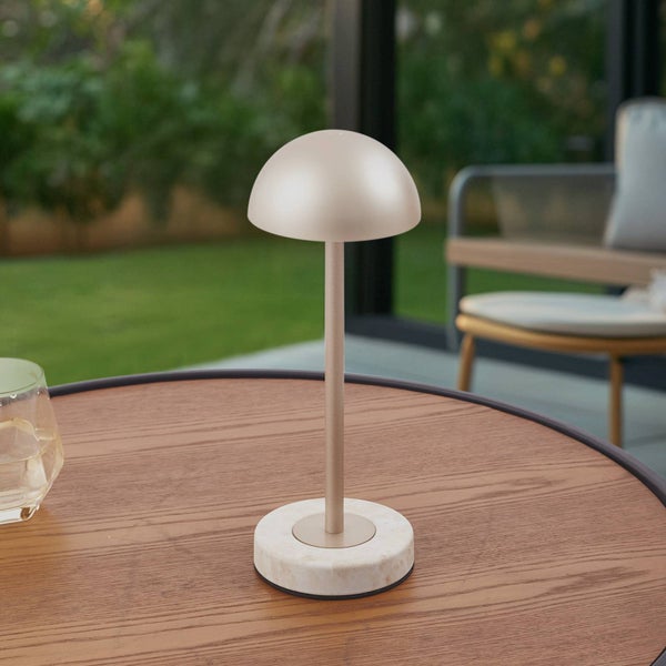 Moderne akkubetriebene Tischleuchte mit pilzförmigem Schirm und rundem Marmorfuß auf einem hölzernen Gartentisch.