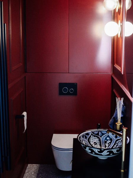 Modernes Badezimmer mit Toilette, Waschbecken mit Muster und roter Wandgestaltung