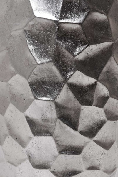 Detailaufnahme einer metallischen Oberfläche mit facettierter geometrischer Struktur