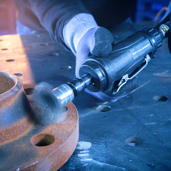 Ein Mann benutzt einen Druckluft-Winkelschleifer von Stahlwerk, um Metall zu schleifen.