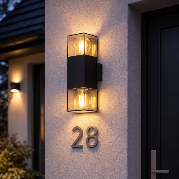 Moderne schwarze Außenwandleuchte aus Metall und Glas mit zwei Leuchtmitteln an einer Fassade über der Hausnummer achtundzwanzig.
